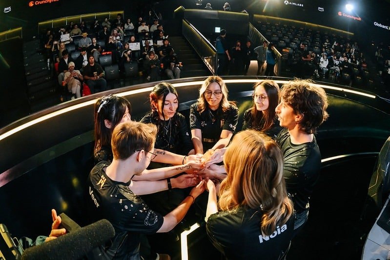 Imagem de membros da lista de VALORANT Game Changers da Shopify Rebellion compartilhando uma reunião de equipe no palco durante um torneio internacional