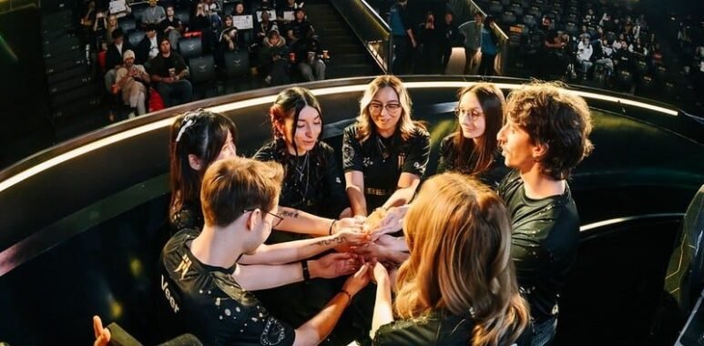 Image of members of the Shopify Rebellion VALORANT Game Changers roster sharing a team huddle on stage during an international tournament