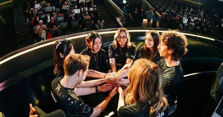 Image of members of the Shopify Rebellion VALORANT Game Changers roster sharing a team huddle on stage during an international tournament