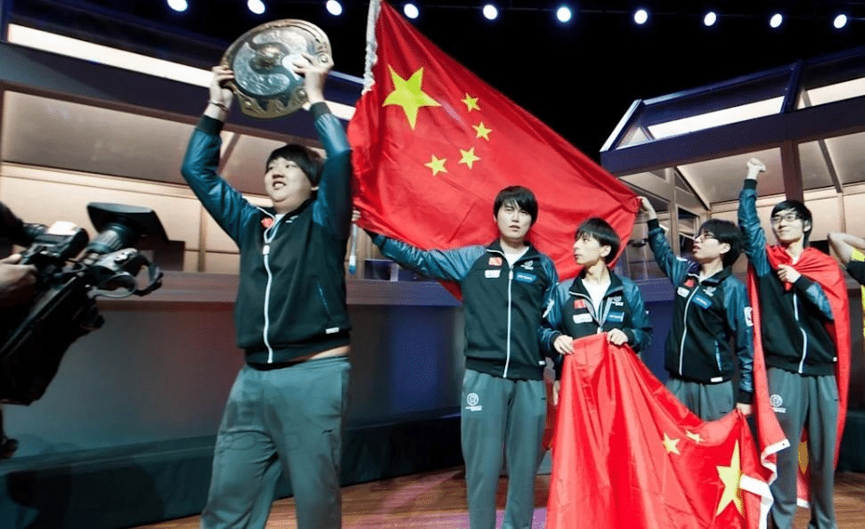 Imagem de Wong 'ChuaN' Hock Chuan segurando o Aegi enquanto o resto da Invictus Gaming agita orgulhosamente uma bandeira chinesa após triunfar na TI2.
