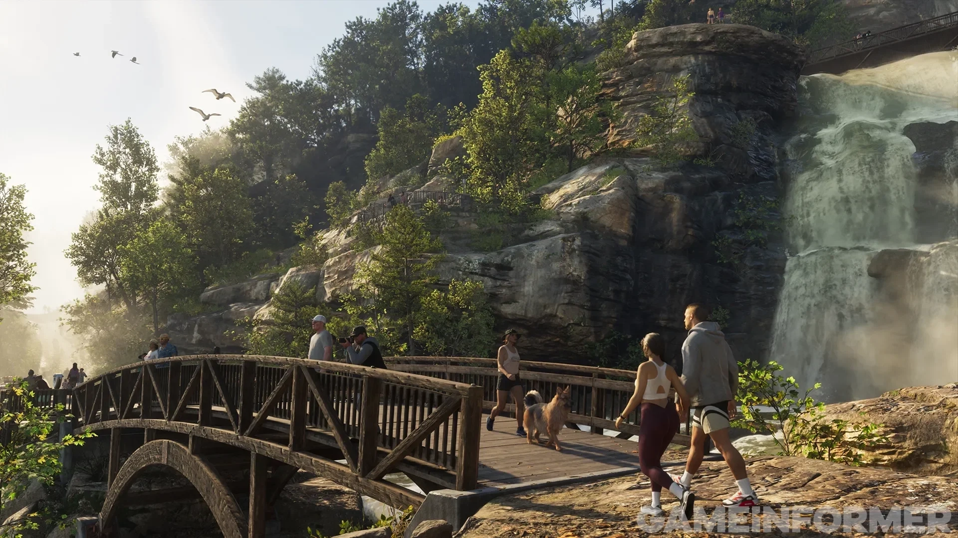 Pedestres, caminhantes e um cachorro atravessando uma ponte de madeira perto de uma grande cachoeira em um exuberante parque estadual montanhoso em Grand Theft Auto VI.   