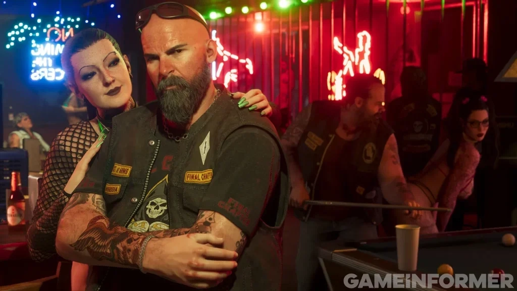 Uma captura de tela de Grand Theft Auto VI apresentada pela Game Informer, mostrando um motociclista careca com barba cheia e óculos escuros dobrados na cabeça, vestindo um colete de couro com remendos dentro de um bar iluminado por neon. Uma mulher de cabelos escuros e roupa de malha se inclina sobre seu ombro, enquanto outros membros do clube jogam bilhar em uma mesa de sinuca ao fundo, com uma marca d'água Game Informer no canto inferior direito.
