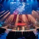 An esports stage for VALORANT Champions Paris with a large screen, red and blue lighting, and empty seating.
