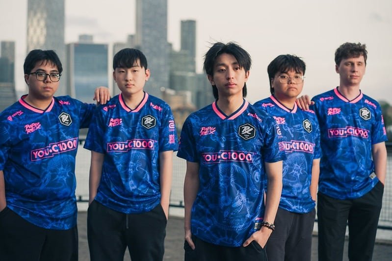 Foto da equipe profissional de esportes eletrônicos Paper Rex posando com suas camisetas azul e rosa.