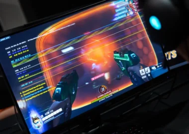 A person wearing a headset playing a first-person shooter game on a monitor.
