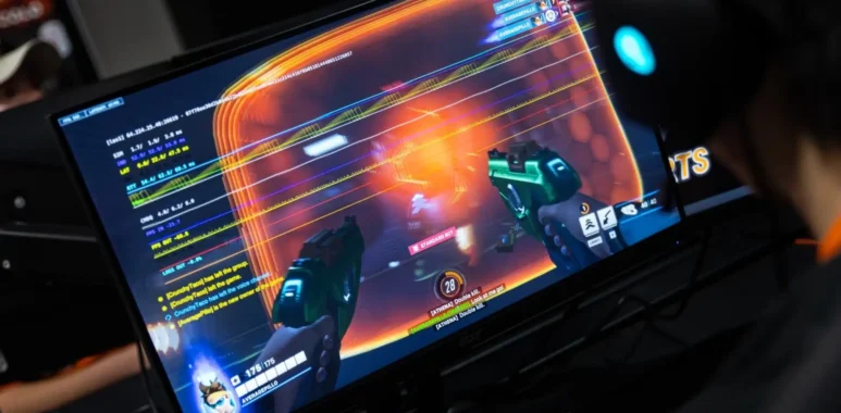 A person wearing a headset playing a first-person shooter game on a monitor.