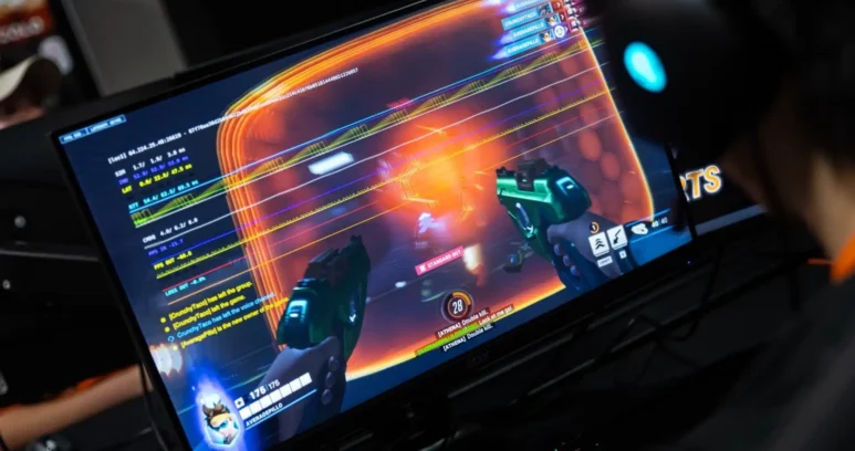 A person wearing a headset playing a first-person shooter game on a monitor.