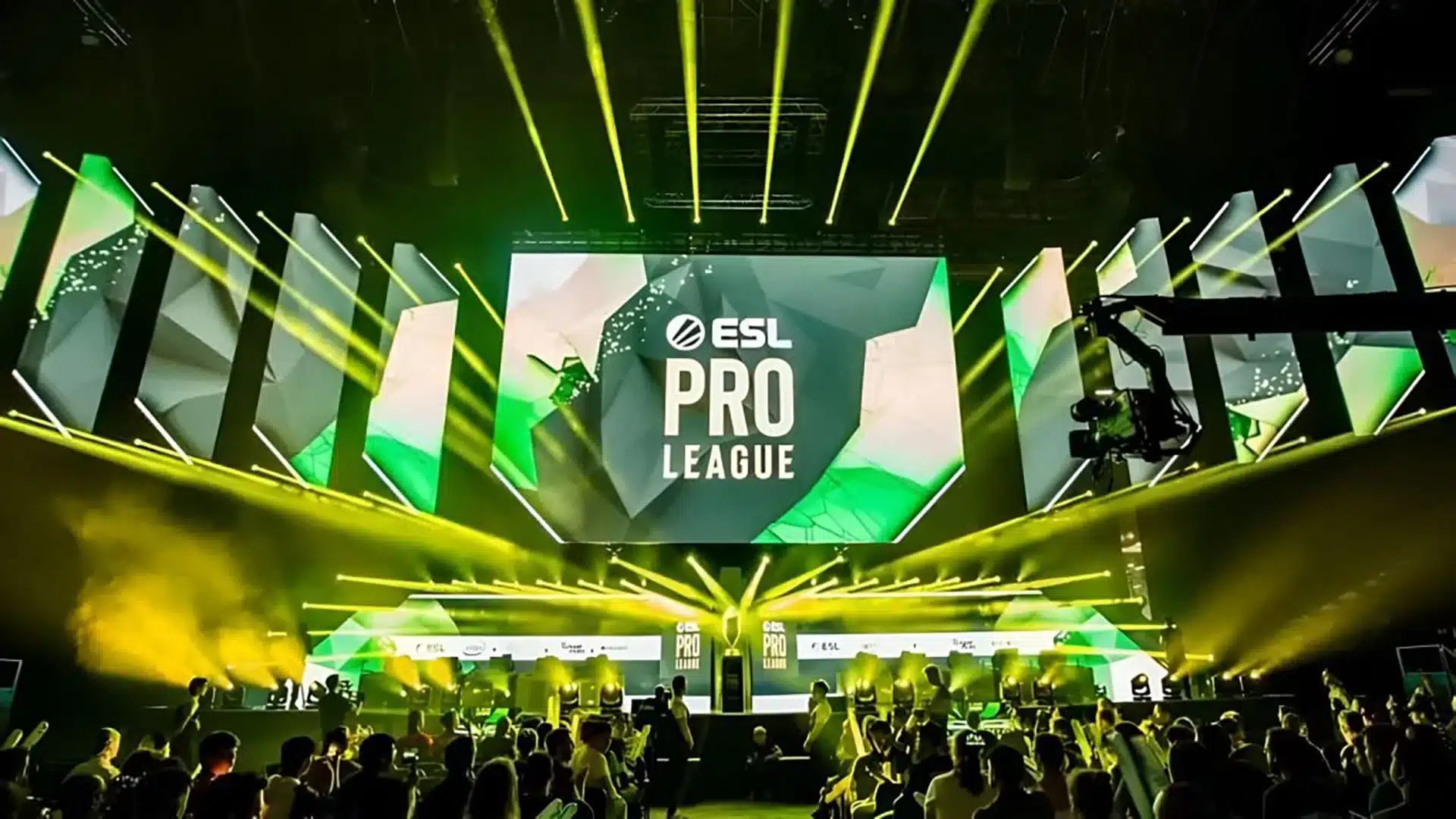 Um palco de torneio da ESL Pro League com telões e holofotes amarelos sobre uma multidão.
