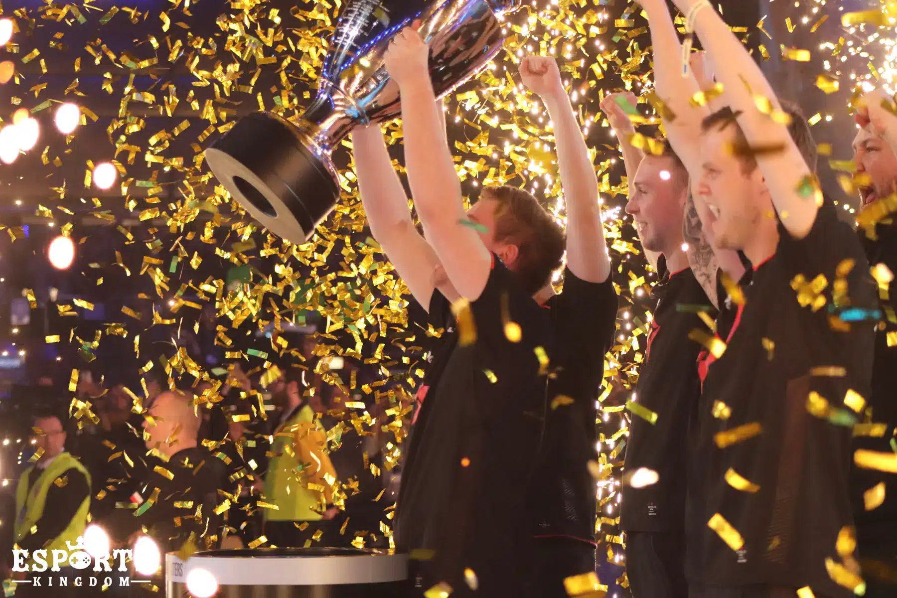 Membros da equipe de esportes eletrônicos Astralis comemoram com um troféu em meio à queda de confetes dourados.
