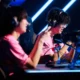 Two professional esports players in pink jerseys wearing headsets at a competition stage.