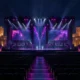 A dramatic CS2 esports tournament stage with violet lighting in a modern Malta arena