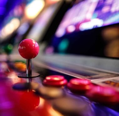 Close-up of an arcade fighting game joystick and buttons under neon lights