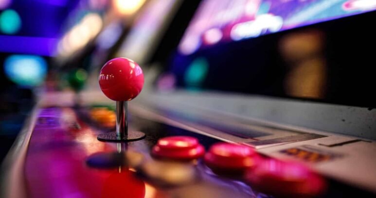 Close-up of an arcade fighting game joystick and buttons under neon lights