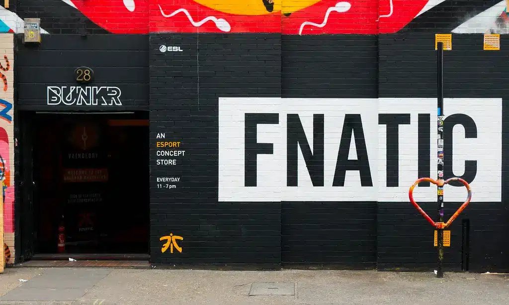 O exterior de uma loja conceito de esportes eletrônicos da Fnatic com o nome da organização em grandes letras pretas sobre fundo branco.