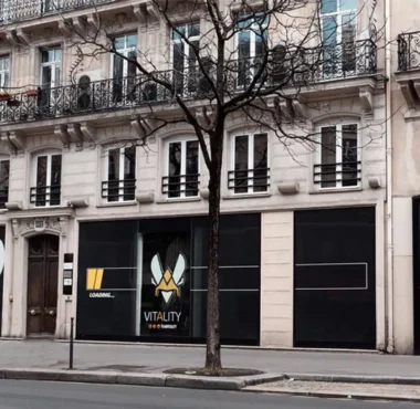 The exterior storefront of Team Vitality V.Hive in Paris, featuring the team's logo and branding on black panels.