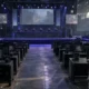 Empty esports tournament venue with unbranded player stations and a central stage