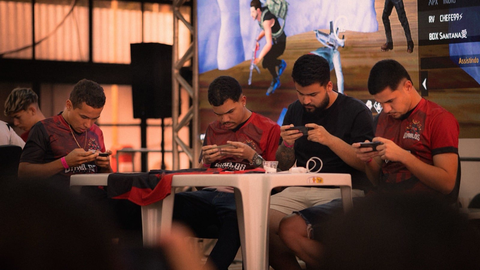 Jogadores competindo em smartphones em um torneio de esportes eletrônicos para dispositivos móveis