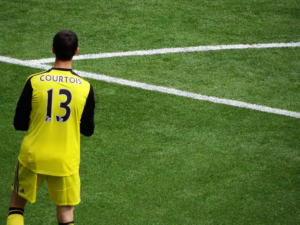 Thibaut Courtois vestindo uniforme amarelo de goleiro com o nome Courtois e o número 13 nas costas.